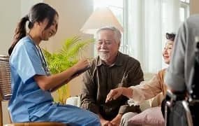 Auxiliaire de vie souriante avec un couple de seniors
